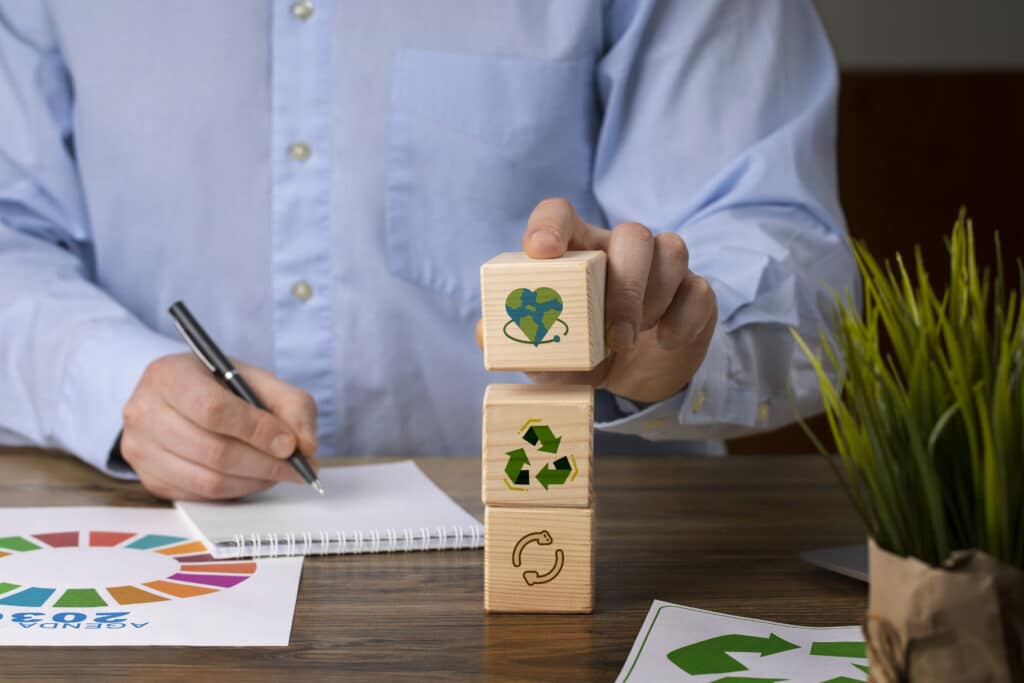 Homem empilhando blocos de madeira com ícones de sustentabilidade, representando práticas ESG; a imagem simboliza o conceito de greenhushing, onde empresas sustentáveis evitam divulgar suas ações por receio de críticas.