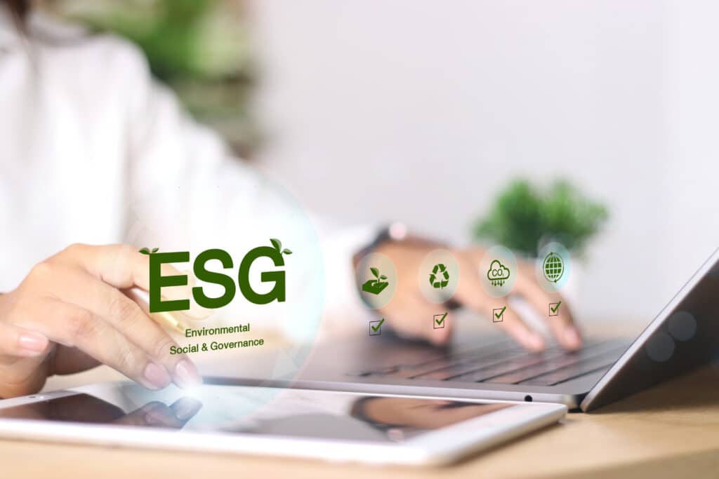 Pessoa usando tablet e notebook com ícones ESG, representando ESG na análise de risco para decisões financeiras sustentáveis.