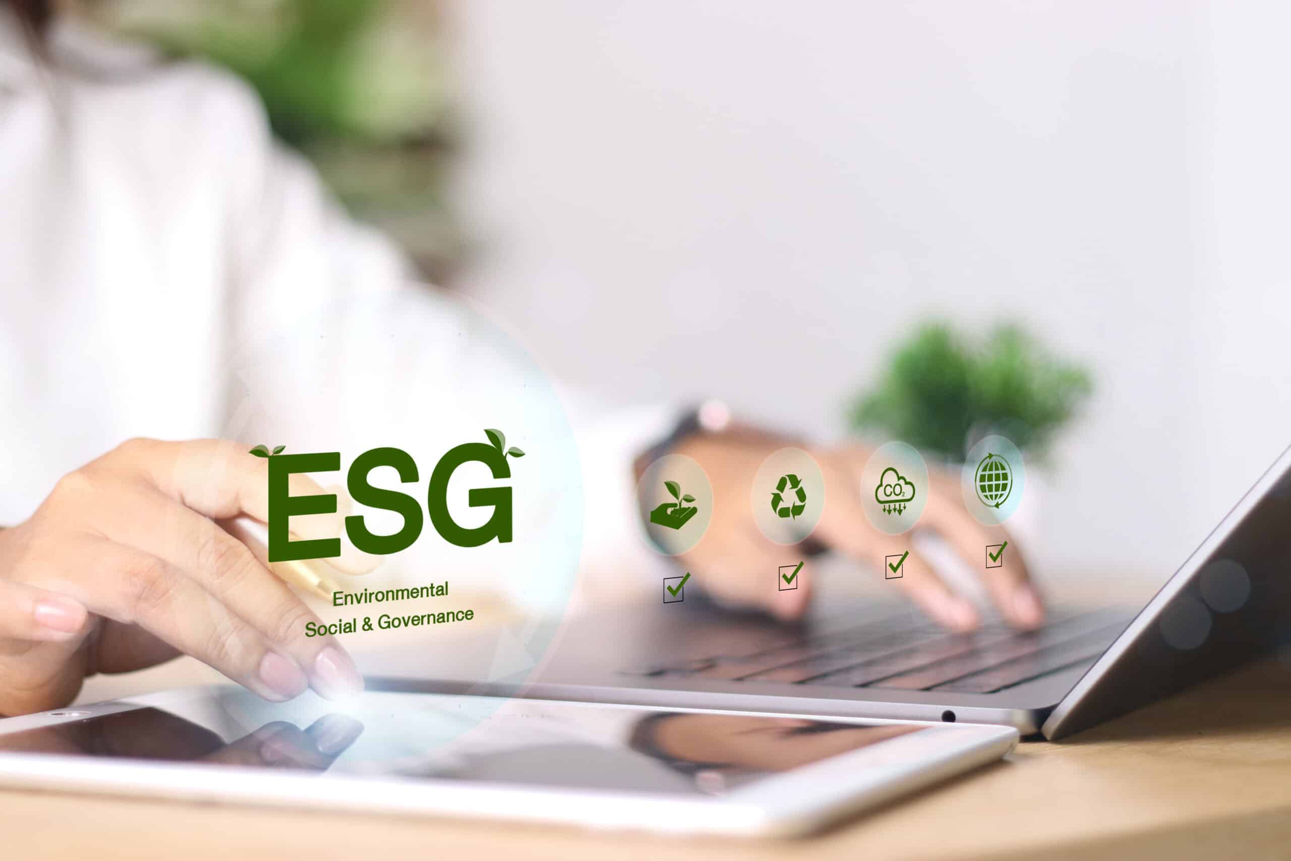 Pessoa usando tablet e notebook com ícones ESG, representando ESG na análise de risco para decisões financeiras sustentáveis.