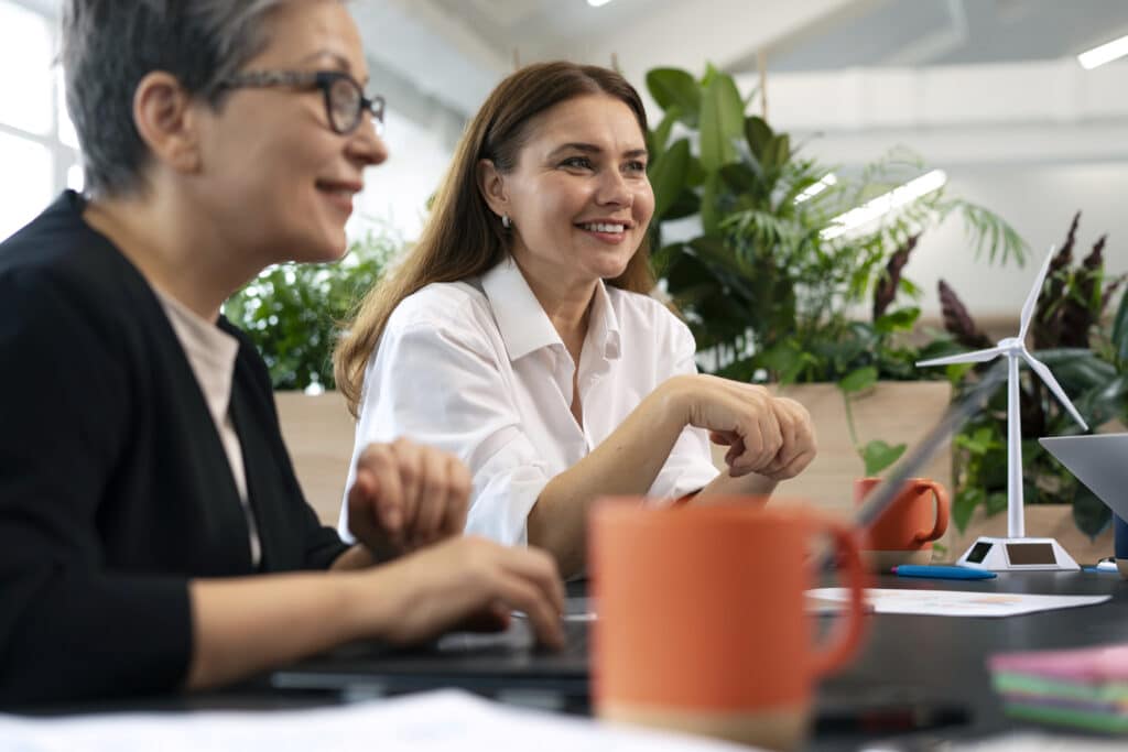 Duas empreendedoras discutindo estratégias de empreendedorismo com propósito em um escritório sustentável